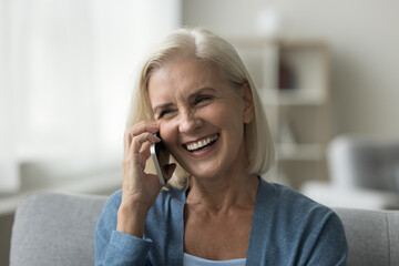 Close up of cheerful senior woman talking on smartphone, spend free time use modern device, having...