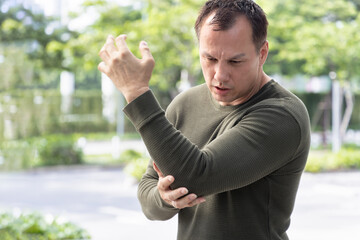 Southeast middle aged asian man suffering from elbow joint pain, concept of tennis elbow or...