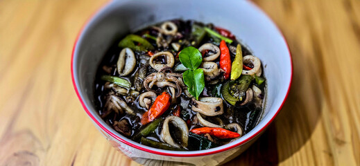 ndonesian home cooking menu, sauteed squid with black ink sauce with spicy seasoning called Tumis Cumi Hitam, including chili, ginger, and lime leaf