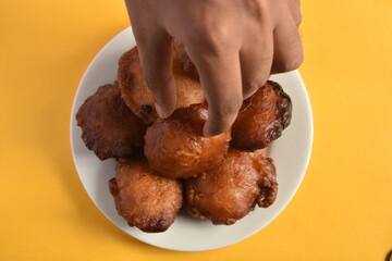 Sri Lankan Kevum dessert on white plate on yellow background, Awrudu Festival treats, sweets, deepfried food, Sinhala and Tamil New Year Food