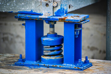 A blue piece of machinery with a spring on it
