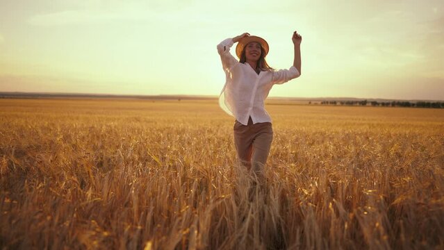Romantic carefree happy woman running on yellow wheat field with spreading flying arms enjoying freedom calmness on rural nature during vacations holidays. Rest, relax in country, activity at sunset.