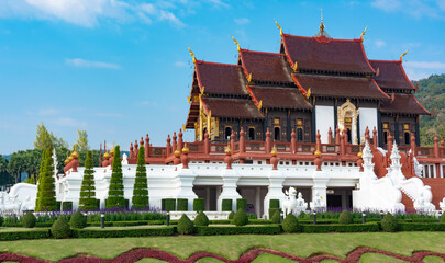 A large building with a red roof and white trim. The building is surrounded by a lush green lawn and has a white facade