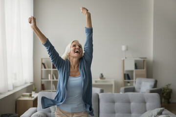 Happy carefree senior woman dancing alone at home, listen favorite music, moves to rhythm in living room, enjoy weekend, rejoicing in retirement. Cheerful female celebrates moving into new apartment