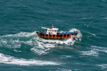Fototapeta premium The Asian boat of the pilot in the high sea during a storm.