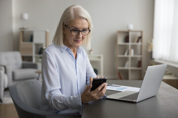 Serious middle-aged businesslady using laptop sit at desk with laptop, lead correspondence by e-mailing with client, chatting on-line by business, check messages, download new e-business application