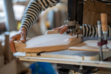 Carpentry workshop, craftsman master working on jig saw. Man joiner hands carved on wood with help...