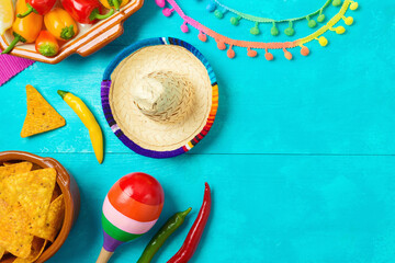 Nacho tortilla chips, peppers, maracas and sombrero hat on blue wooden background. Mexican party Cinco de Mayo holiday celebration. Top view, flat lay - 783845312