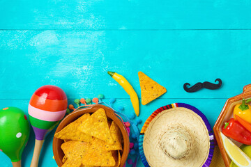 Nacho tortilla chips, peppers, maracas and sombrero hat on blue wooden background. Mexican party Cinco de Mayo holiday celebration. Top view, flat lay - 783845323