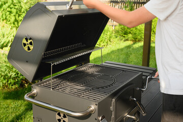 New portable charcoal barbecue grill for summer party. Man check equipment. Outdoors.