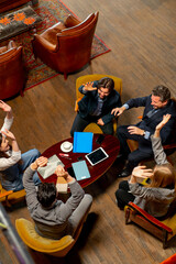 top shot in large beautiful hall office workers sitting on chairs putting their hands together in...