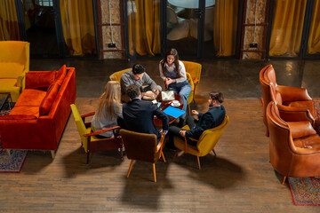 top shot in large beautiful hall office employees sitting on yellow chairs discuss a deal