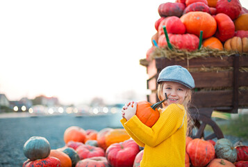 Fototapeta na wymiar Happy little girl at the autumn pumpkin patch background. Having fun. Toned in retro style