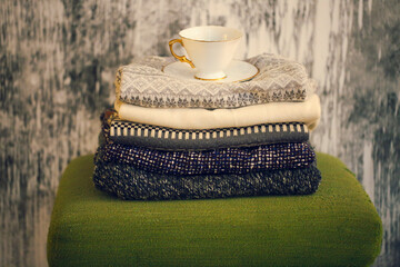 Pile of knitted warm grey and white blankets, scarves and woolen sweaters for winter or fall cold...