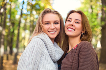 Obraz premium Fashionable beautiful young girlfriends walking together in the autumn park background. Having fun and posing.