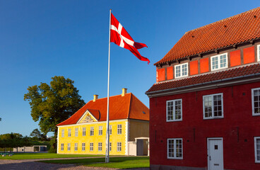 Danish flag waves over Royal Barracks at sunset in Copenhagen, Denmark, Kronprinsessegade Park