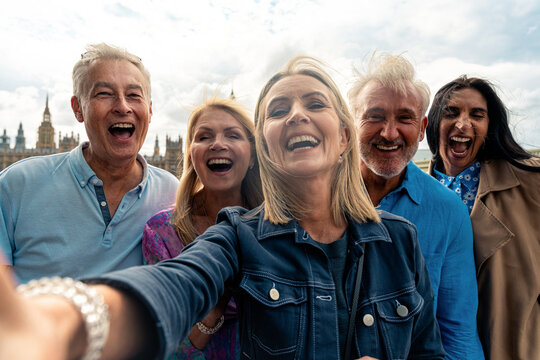 Group of seniors take a pov selfie laughing happily and carefree. Old friends spending time together in the main parts of london, visiting the westminster area and st. james park.