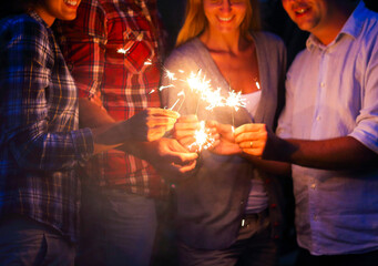 Young people with sparklers having fun on outdoor party