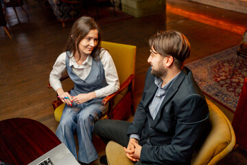 in the recreation area sitting on yellow chairs a businessman makes deal with a female director...