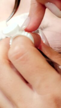 4k vertical high angle view video of beautician putting lashes extension to a beautiful woman. Close up. Stickers on eyebags. Unrecognizable hands from beautician.