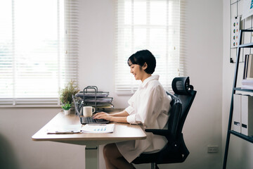 A woman is sitting at a desk with a laptop and a cup of coffee