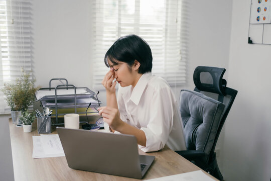 A woman is sitting at a desk with a laptop and a computer mouse