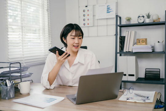 A woman is talking on her cell phone while sitting at a desk