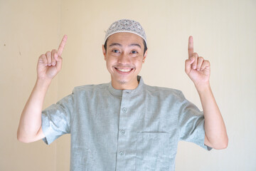 Moslem Asian man pointing the link gesture when Ramadan celebration. The photo is suitable to use for Ramadhan poster and Muslim content media.