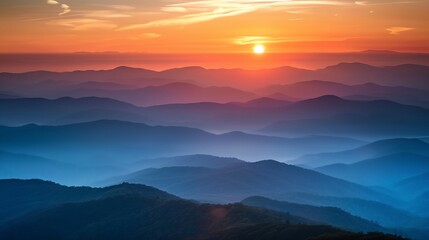 Obraz premium a sunset over a mountain range with a bright orange sun in the distance and a hazy sky above it