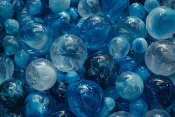 A bunch of blue and white marbles are floating in a blue liquid. The marbles are of different sizes and shapes, creating a visually interesting and dynamic scene