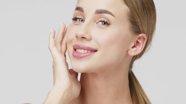 Portrait of a young beautiful woman with smooth healthy skin, she gently touches her face. Cosmetics, spa and skin care products advertising concept.