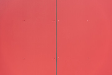 bright red metal background door or wall with vertical line in the middle and screws