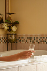 Woman Relaxing in the Bathroom Spa Tub with a Glass of Sparkling Champagne and Candles.
