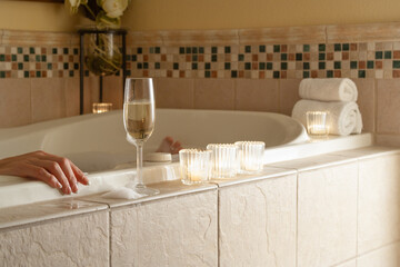 Woman Relaxing in the Bathroom Spa Tub with a Glass of Sparkling Champagne and Candles. - 783895540