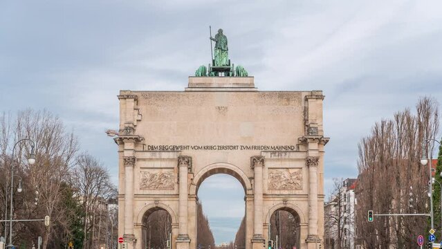 The Siegestor or Victory Gate in Munich is a memorial arch, crowned with a statue of Bavaria with a lion quadriga timelapse. Traffic on the street around the monument. Back view. Germany