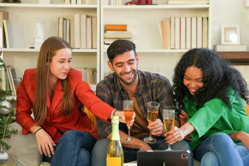 Group of young adults having a festive time, engaging with technology and enjoying drinks by a...