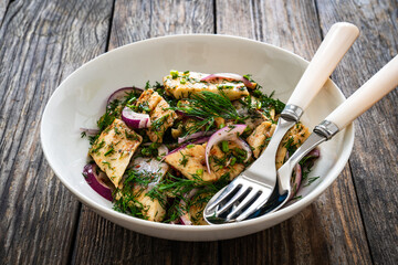 Marinated herring fillets with dill and red onion on wooden table
