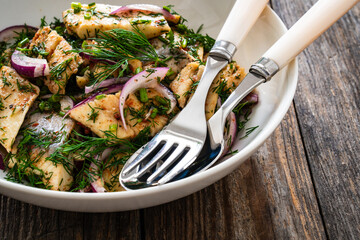 Marinated herring fillets with dill and red onion on wooden table
