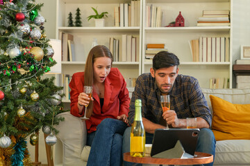 Amidst holiday decorations, a couple shares a cheerful toast with flutes of bubbly, reveling in the...