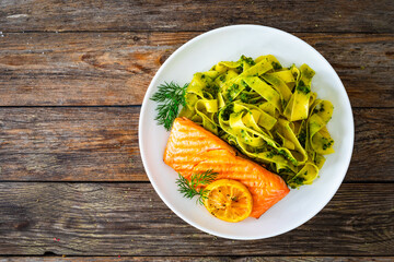 Pappardelle with grilled salmon steak and basil pesto on wooden table
