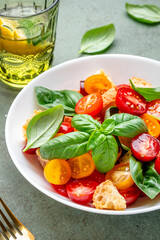 Simple italian salad with with stale bread, cherry tomatoes, olive oil, sea salt and green basil white plate, stone table background, top view - 783906527