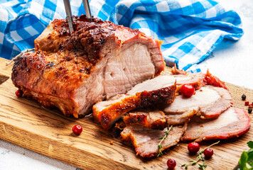 Baked festive pork sirloin with spices and cranberries for sauce, served and sliced on wooden cutting board, white table background, top view - 783906721