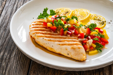 Grilled chicken breast and fresh vegetables on wooden table
