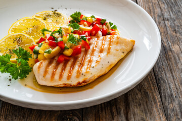 Grilled chicken breast and fresh vegetables on wooden table
