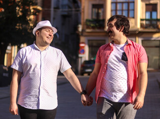 Couple of gay men holding hands walking down the street, one of them laughing happily, outdoor,...