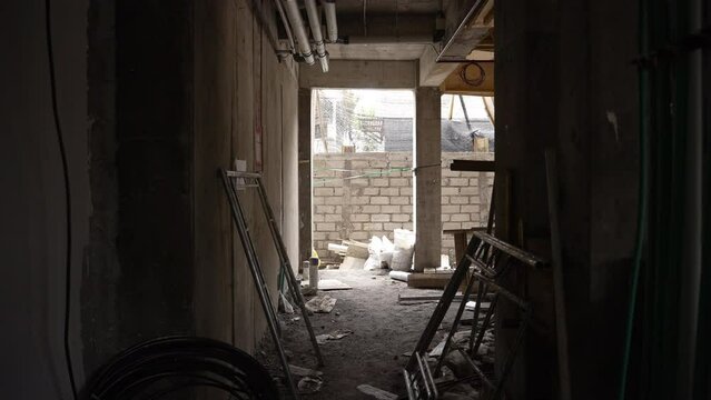 Construction site corridor with electrical fittings, pipes and materials. Unfinished building from inside, works in progress