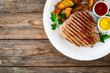 Grilled beef sirloin steak with baked potatoes on wooden table
