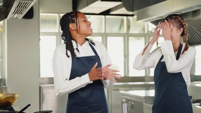 Girlfriend chef helps woman friend tie apron in a restaurant kitchen. Two adults in uniform prepare for food education standing with a painting ready for service.