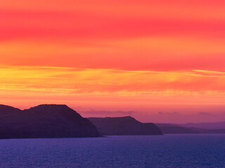Naklejka na ściany i meble Fiery Dawn Clouds on an April Sunrise over the Jurassic Coast