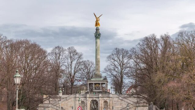 Peace Column with golden Angel of Peace statue (Friedensengel) timelapse, people on the bridge over Isar river looking to rope walker. Public park in the Bavarian capital. Germany, Munich, Bogenhausen